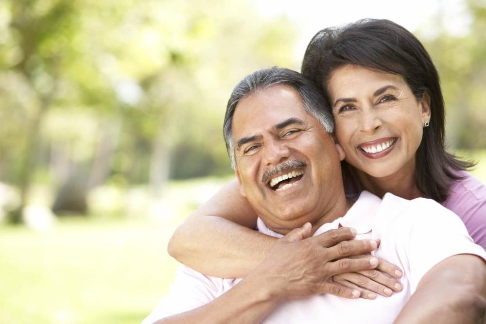 Older man and woman smiling after getting dental implants in barrie