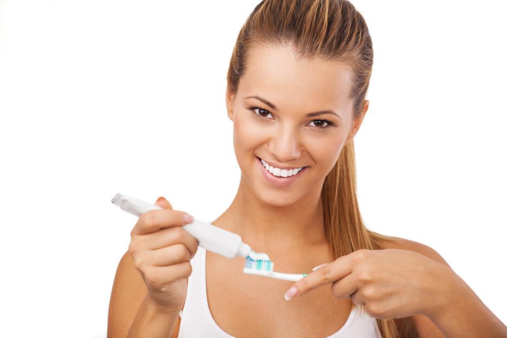 woman putting toothpaste on toothbrush