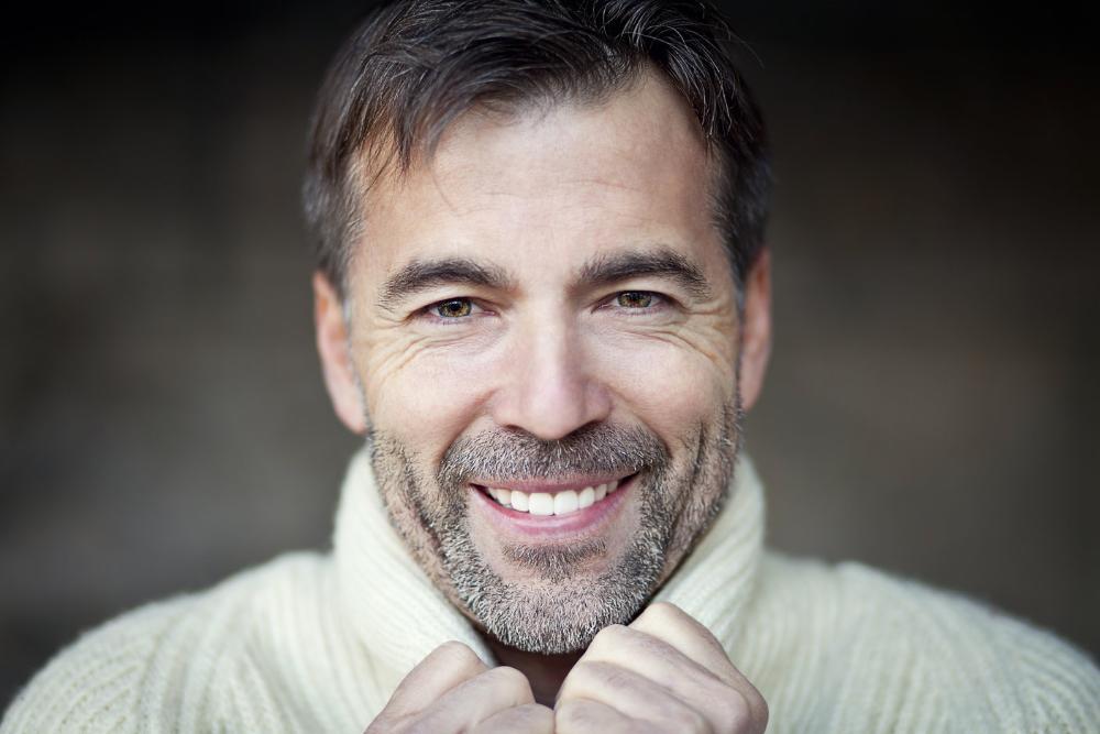 man in white sweater smiling after getting chipped tooth fixed