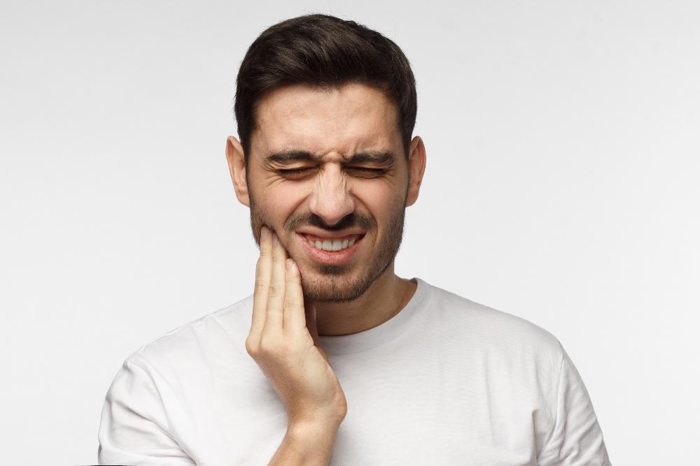 Man holding jaw from tooth pain during dental emergency