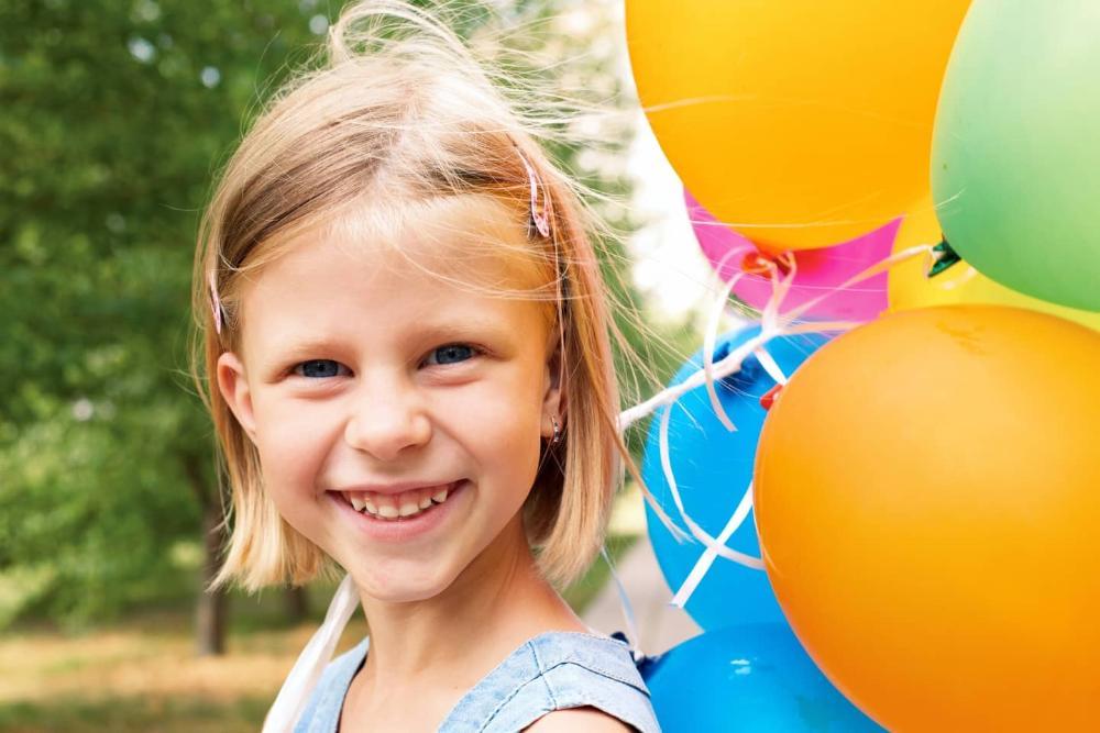 young girl smiling while holding balloons at a Barrie park