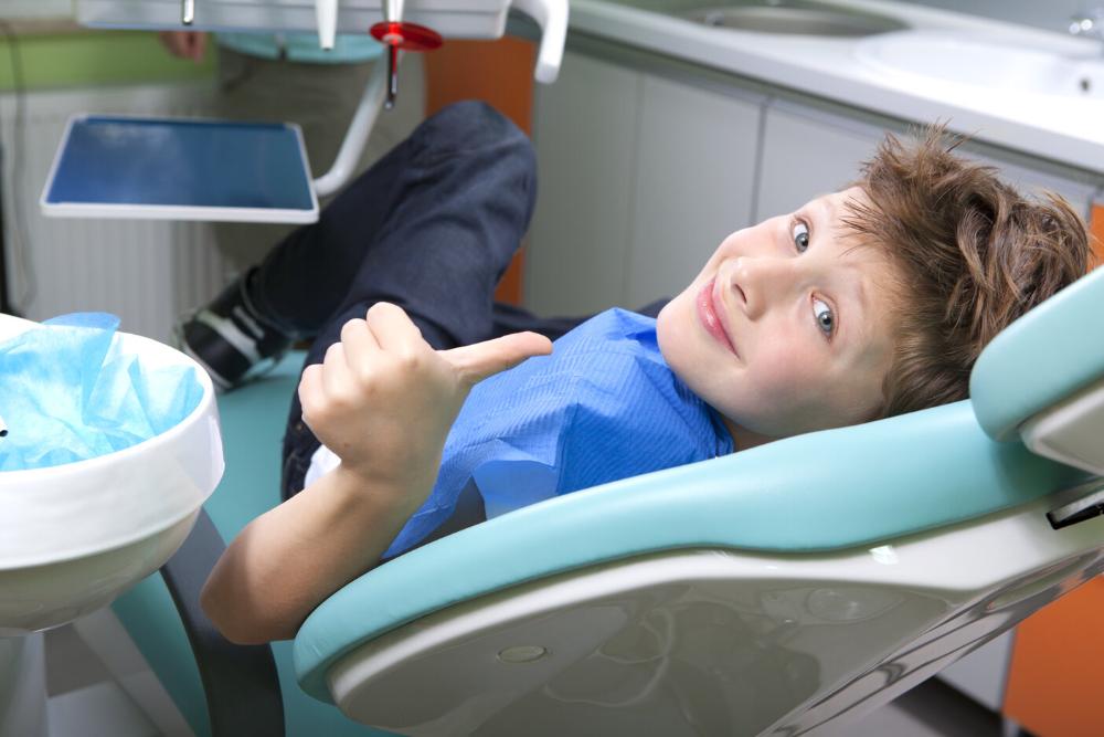 young boy giving a thumbs up in a dental chair 