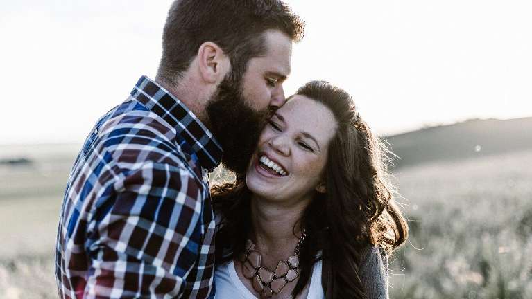 man kissing woman on cheek while she laughs