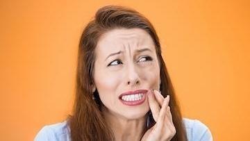 Woman holding jaw from tooth pain