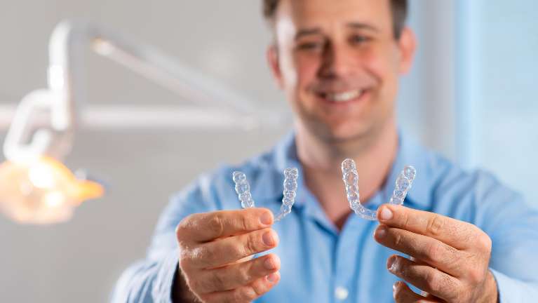 man holding two invisalign clear aligners from Barrie dental clinic