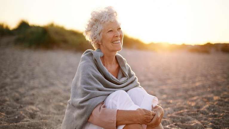 older barrie woman smiling while sitting on beach