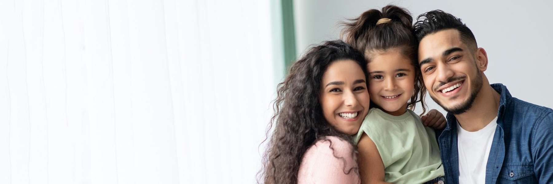 mom, dad, and young daughter smiling