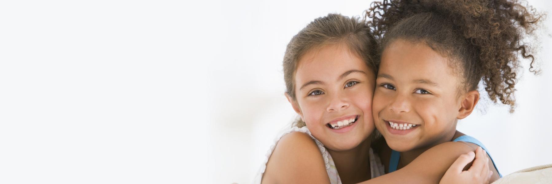 Two young girls hugging after getting teeth cleaned in barrie