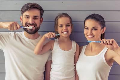 dad, mom, and daughter brushing teeth